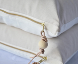 Pillow detail showing YKK brass zipper, genuine leather cord, and wooden bead.