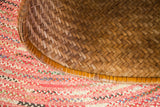 Close-up of the hand-woven herringbone texture and curved rim of an antique bamboo basket.
