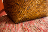 Aged, hand-woven diagonal bamboo weave texture on the vintage basket's base.