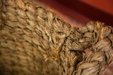 Close-up of the nubby texture and braided handles of the vintage basket with grey patina.