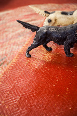 Distressed black pointer dog doorstop with chipped paint and textured surface, on red textile.