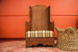 Antique oversized settle chair, upholstered in neutral plaid fabric with wide plank wood.