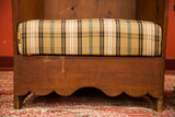 Scalloped base and aged wide-plank wood of an antique settle chair leg.