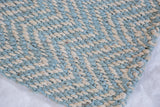 Close-up of hand-braided jute weave with light blue and natural beige geometric pattern.