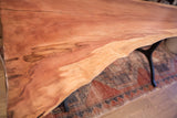 Warm wood grain detail along the natural, flowing live edge of a redwood table.