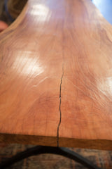 A long natural crack follows the warm wood grain of the live edge redwood table.