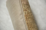 Pillow edge detail: distressed Oushak rug fragment pile and woven beige backing.