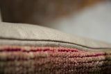 Distressed vintage Oushak rug fragment with muted pink texture, joined to a neutral woven backing.