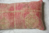 Distressed vintage Oushak rug fragment pillow texture with faded rose and beige tones.