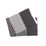 Folded black and white modern blanket displaying diverse geometric patterns.