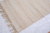 Hand-woven texture and natural jute fiber fringe on the blanched rug corner.