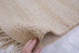 Blanched jute carpet's textured natural fiber weave and hand-finished edge.