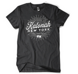 Katonah NY Finest Folks unisex tee in charcoal gray with a white sunburst graphic print.