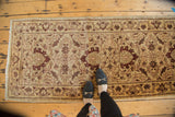 An Egyptian rug runner's Sultanabad design of serrated leaves and vinery, shown for scale on a floor.