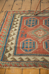 Geometric blue motifs, reciprocating border, and worn madder red pile of antique Kazak rug.