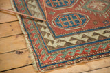 Antique Kazak rug corner, showing geometric reciprocating border in contrasting colors and worn fringe.