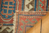 Reciprocating border and tattered fringe on the lifted corner of an antique Kazak rug.