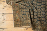 Intricate border motifs and time-softened charcoal boteh field on an antique Tabriz rug.