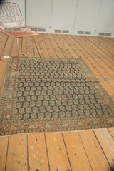 Antique Tabriz rug's bottom edge, intricate charcoal boteh field, multi-hued border, and fringe.