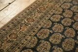 Detail of hand-knotted antique Tabriz rug: intricate germinating plant botehs on a charcoal field.