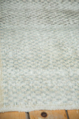 Close-up of distressed Oushak runner's textured ivory, charcoal, and sea foam checker motif.