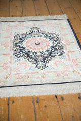Ivory fringe and dark navy border with intricate blush floral motifs on a Hereke silk rug.