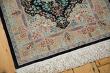 Intricate floral blossoms and ivory fringe on the vintage Hereke rug's navy border.