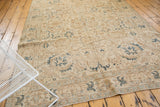 Faded ivory and teal geometric motifs on a distressed vintage Tabriz rug corner.