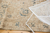 Distressed Tabriz carpet corner, ivory and coffee brown with dark navy teal serrated patterns.