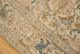 Distressed vintage Tabriz carpet detail showing ivory, brown, and dark navy teal rectilinear motifs.