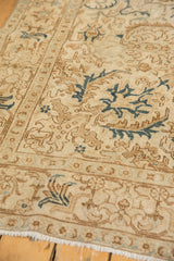 Distressed vintage Tabriz rug featuring serrated geometric patterns in ivory, brown, and navy teal.
