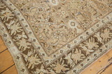 Angled view of a vintage Malayer corner showing the oversized floral border and worn, low pile.