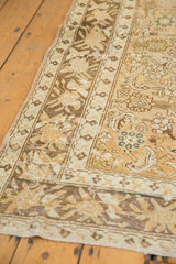 Worn corner of a distressed Malayer carpet showing intricate sand and bronze borders.