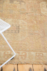 Mostly even low pile and secured end of a distressed Oushak rug, sand and blush tones.