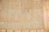 Distressed Oushak rug corner showcasing low pile texture, dusty sand, and slate gray tones.