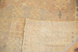 Vintage Oushak carpet folded, showing low pile with soft gray and blush tones, and hand-knotted foundation.