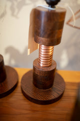 Close-up on the Edison lamp's dark wood grain and reflective copper coil detail.