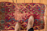 Antique Turkish Yastik rug displaying hard wear, exposed foundation, and tattered side.