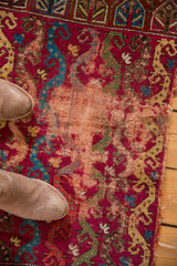 Exposed foundation and wear, raspberry red, sapphire blue, on antique Yastik rug.