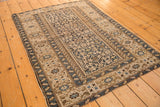 Angled corner of an antique Caucasian rug displaying navy and sand geometric serpent motifs.