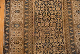 Antique Caucasian rug's intricate geometric field in navy, sand, sky blue with visible wear.