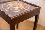 Dark wood corner of the painted vintage end table, displaying surface wear and dot pattern.