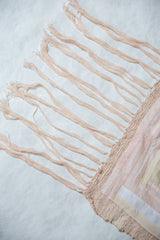 Soft pink fringe and textured woven edge of a handmade textile art quilt.