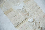 Handmade Lea Thomas weaving detail: flowing natural cream threads with a thick, textured yarn element.