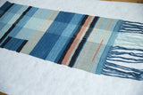Detail of Lea Thomas weaving, highlighting texture of hand-dyed blue, gray, black, and muted orange yarns.