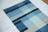 Corner detail of Lea Thomas weaving with variegated blue and black striped texture.