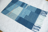 Lea Thomas weaving texture with hand-dyed blue yarns and a vibrant orange accent.