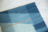Lea Thomas weaving detail: abstract blue blocks, varied textures, and orange line.