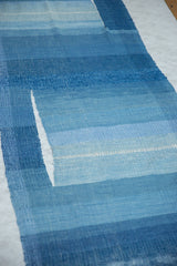 Close-up of handwoven blue textile with varying shades and a vertical design split.