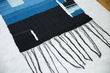 Dark hand-dyed fringe on the black section of Lea Thomas's handmade abstract weaving.